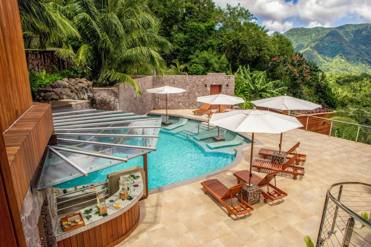 A pool with loungers, umbrellas, and lush hillside scenery at Ladera Resort.