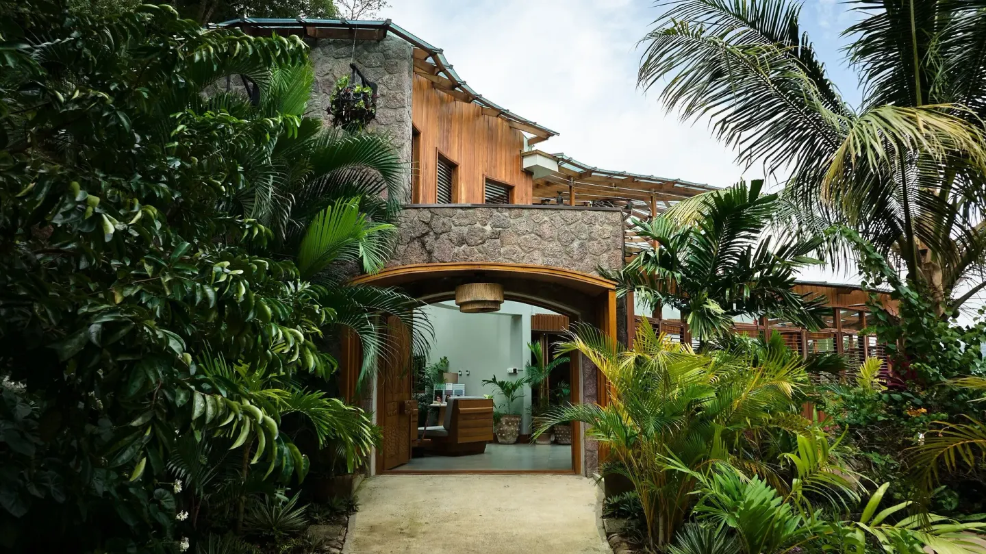 Stone and wood resort building framed by tropical plants at Ladera Resort.