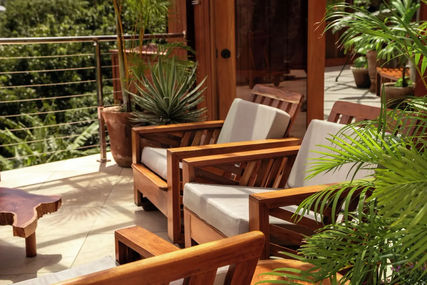 Cushioned wooden lounge chairs sit on a leafy terrace at Ladera Resort.