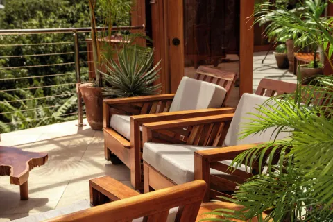 Cushioned wooden lounge chairs sit on a leafy terrace at Ladera Resort.