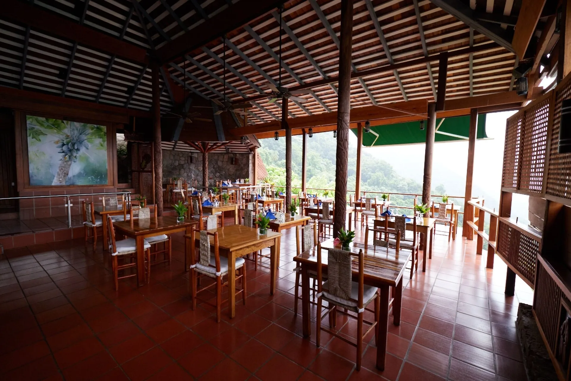 An open-air dining room with wooden tables and hillside views at Ladera Resort.