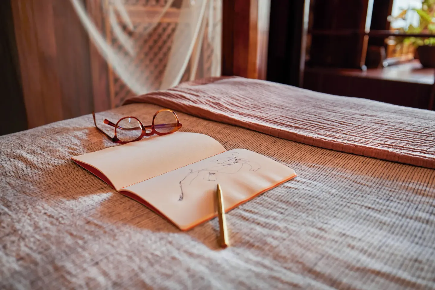 Open notebook and glasses on the Gros Piton Suite bed at Ladera Resort.