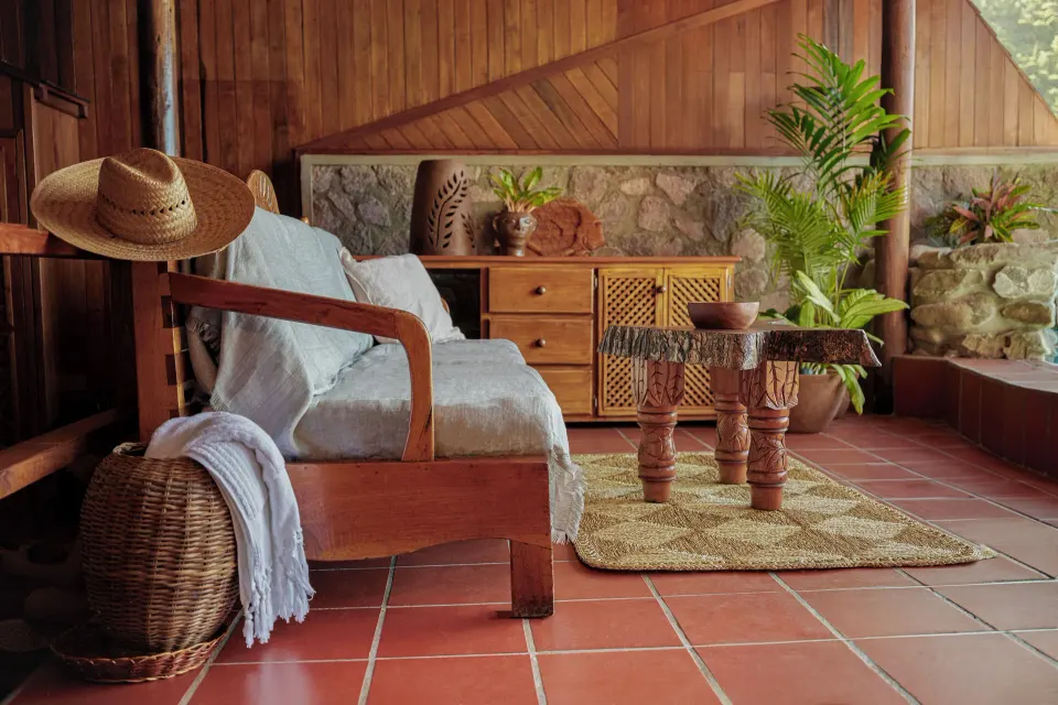 Seating area with wood furniture and tropical plants in the Gros Piton Suite at Ladera Resort.