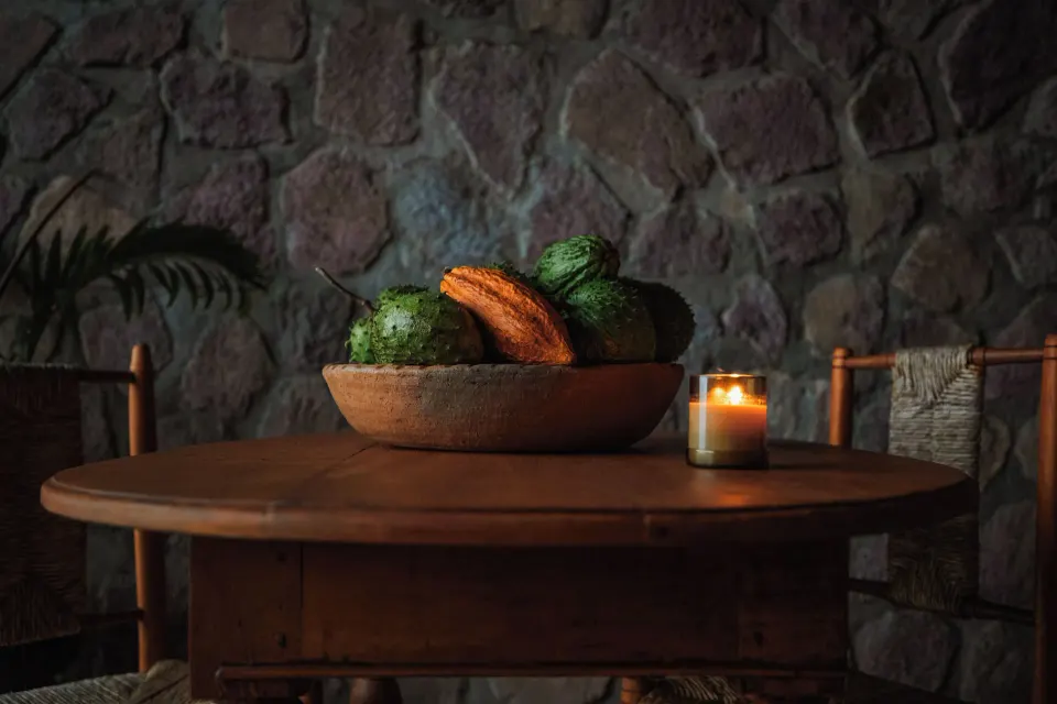 Round wooden table with a fruit bowl and candle in the Hilltop Dream Suite at Ladera Resort.