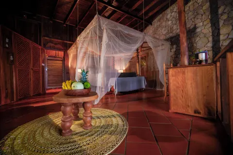 Hilltop Dream Suite bedroom with a netted bed and fruit table at Ladera Resort.