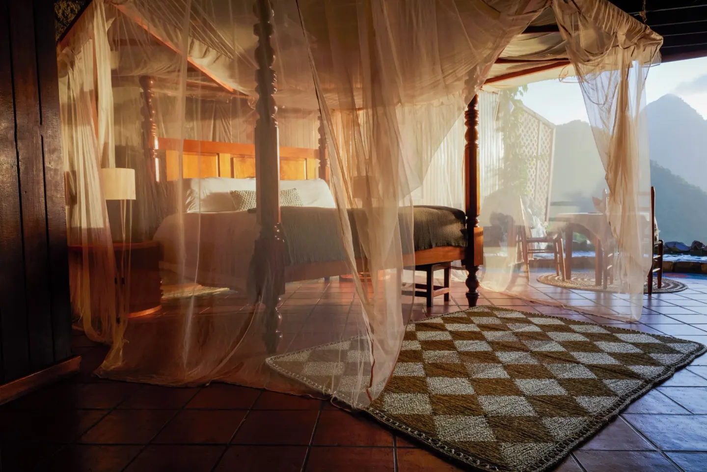 Rainbow Suite four-poster bed with mosquito netting and open terrace view at Ladera Resort.