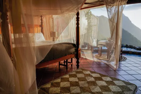 Rainbow Suite bed behind sheer netting with plunge pool and mountain view at Ladera Resort.