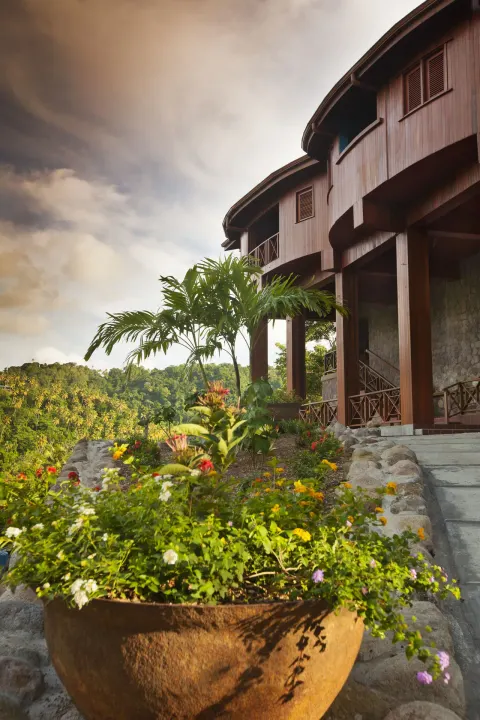Exterior of suites at Ladera Resort with tropical flowers, palms, steps, and wooden balconies.
