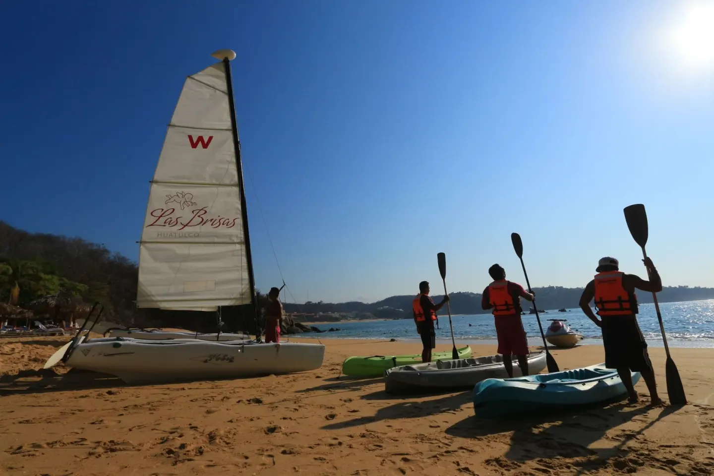 Guests prepare kayaks beside a sailboat on the beach at Las Brisas Huatulco.