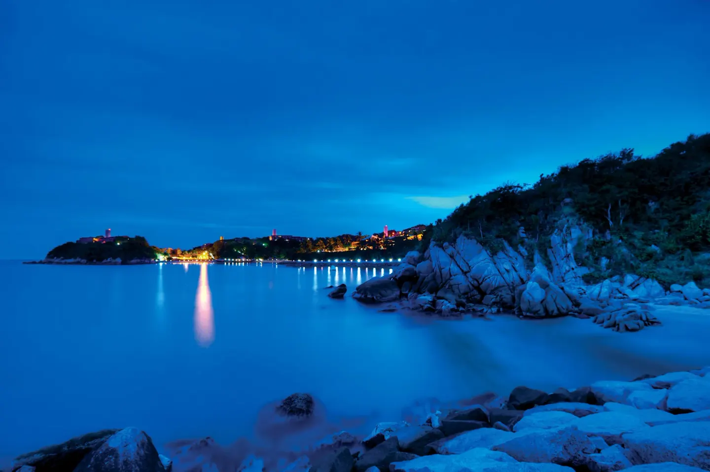 Blue-hour bay view with rocky shoreline and resort lights at Las Brisas Huatulco.
