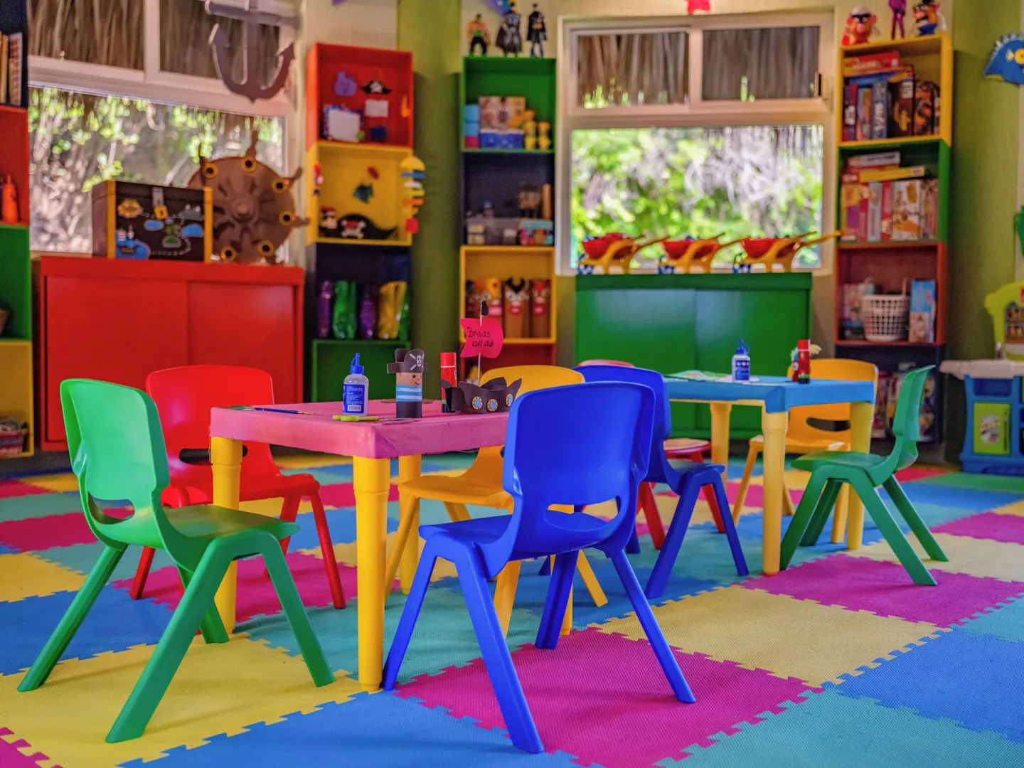 A colorful children’s activity room with small tables is shown at Las Brisas Huatulco.
