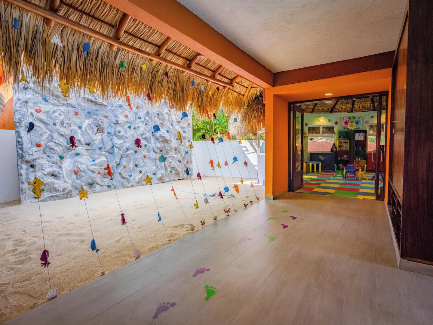 A children’s play area entrance with climbing wall is shown at Las Brisas Huatulco.