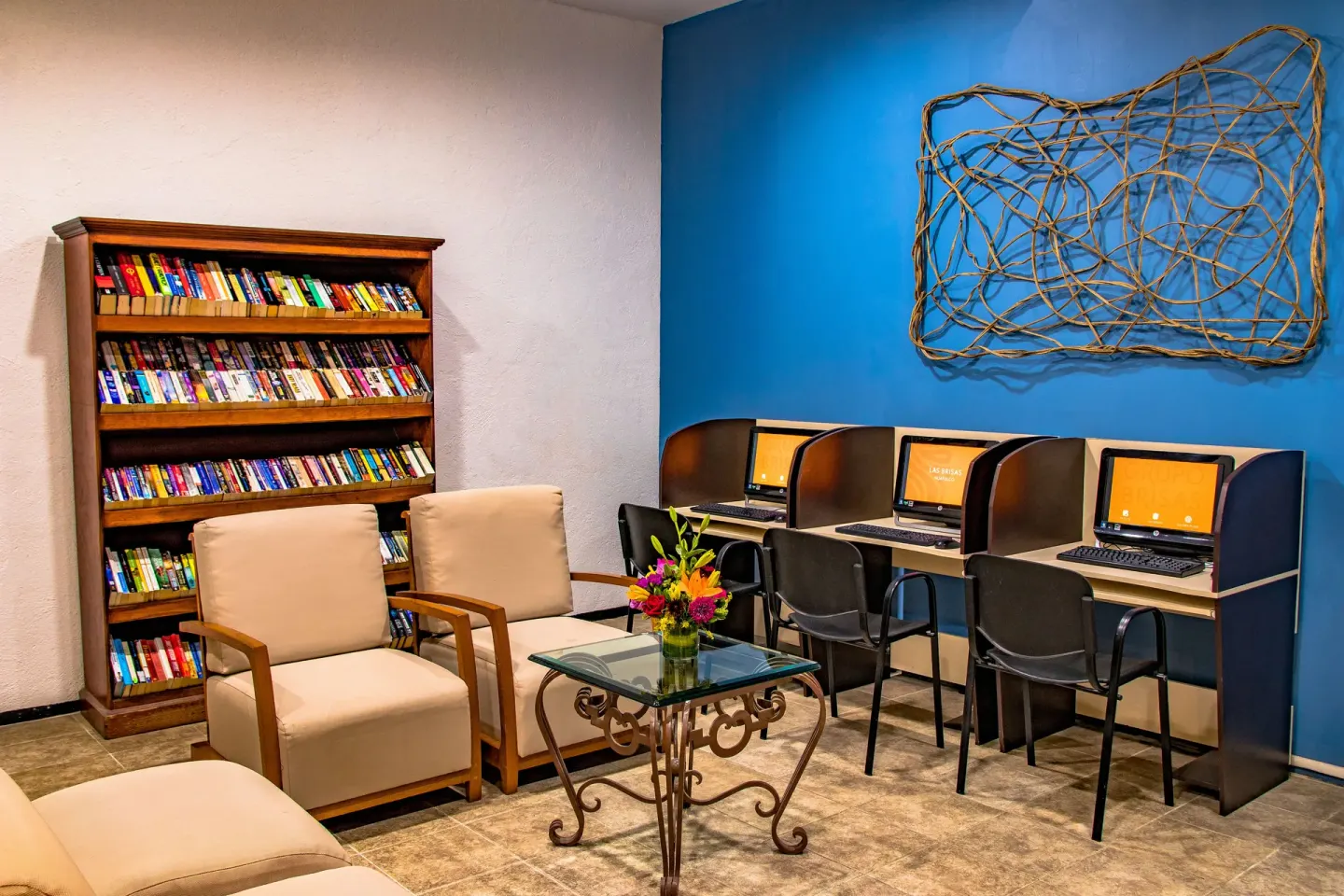 Library and computer area with bookshelf and lounge chairs at Las Brisas Huatulco.