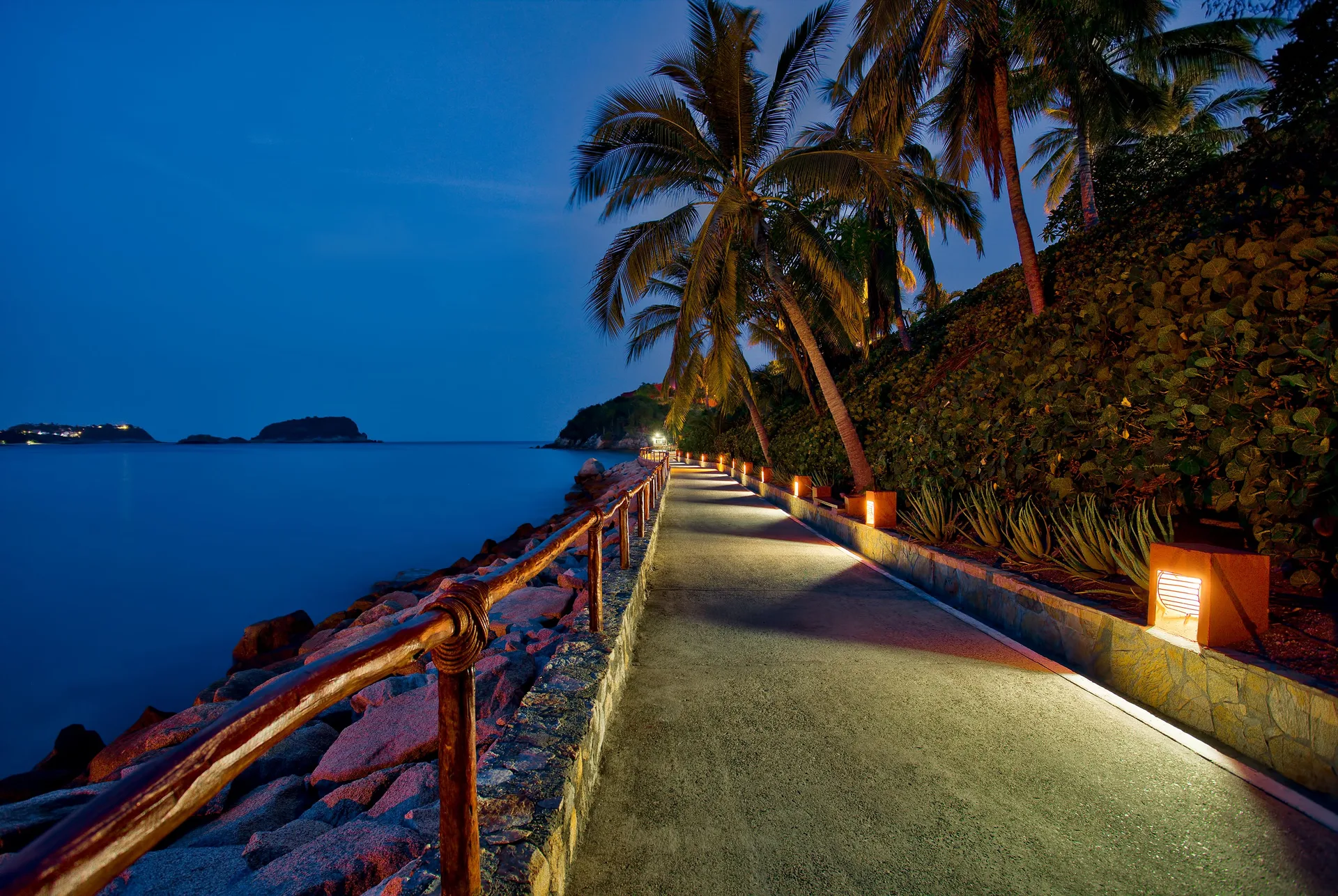 Lighted seaside walkway with palms and ocean views at Las Brisas Huatulco.