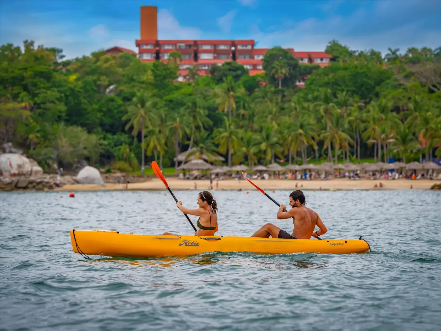 Two guests paddle a yellow kayak offshore at Las Brisas Huatulco.