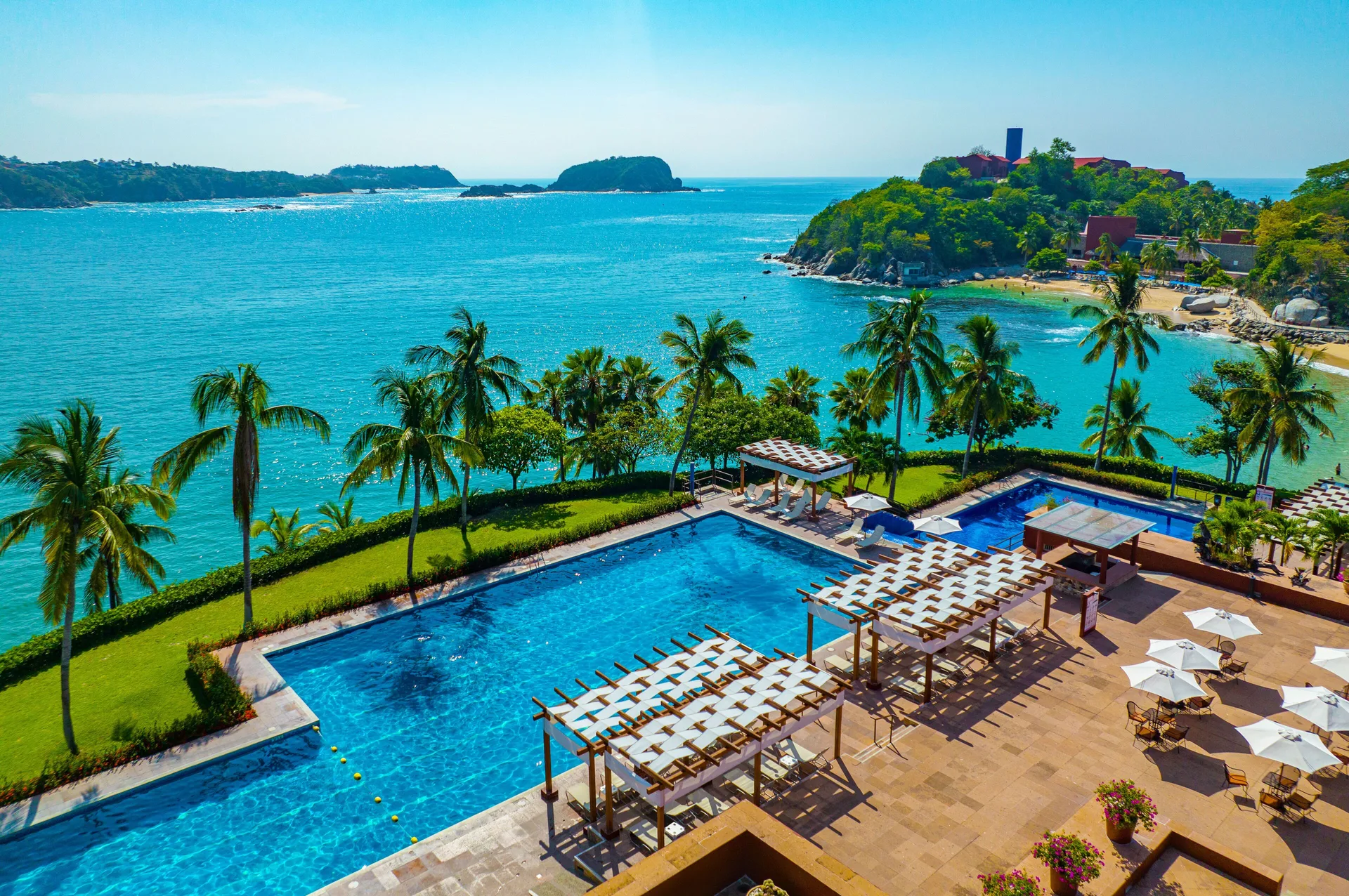 Oceanfront pool, palms and bay views at Las Brisas Huatulco.