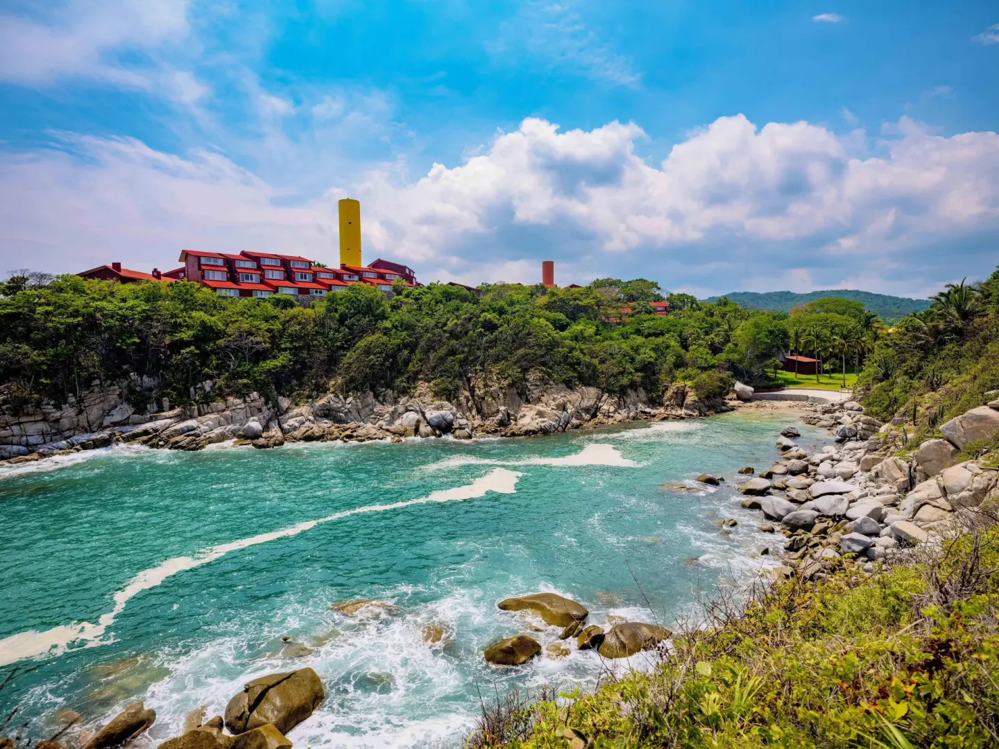 Turquoise rocky bay below hillside resort buildings at Las Brisas Huatulco.