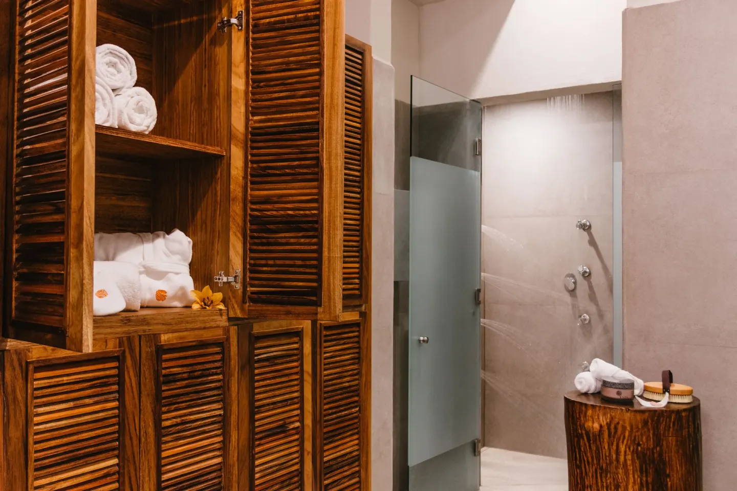 Spa shower area with wood lockers, towels and frosted glass door at Las Brisas Huatulco.