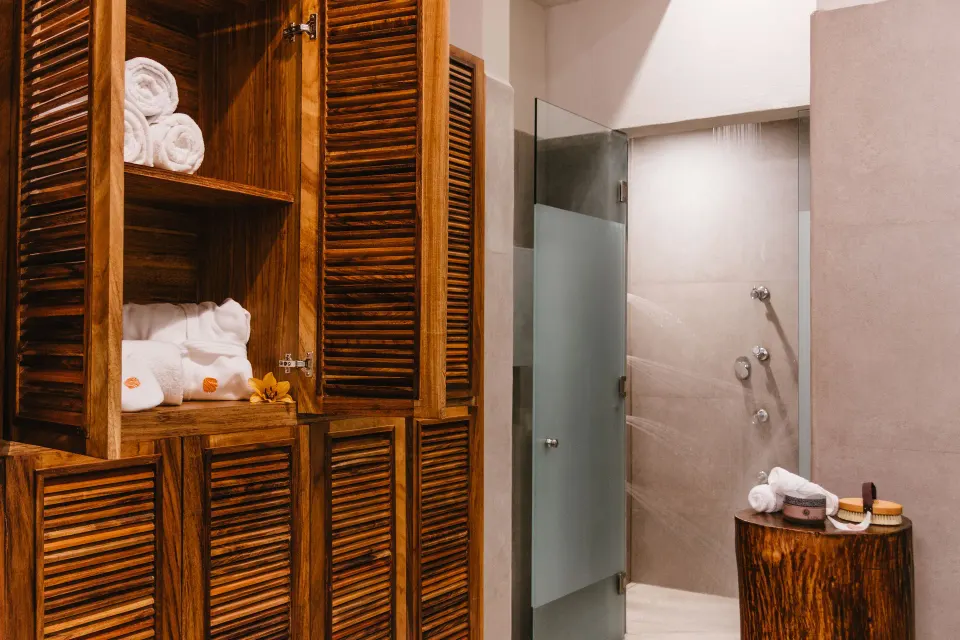 Spa shower area with wood lockers, towels and frosted glass door at Las Brisas Huatulco.