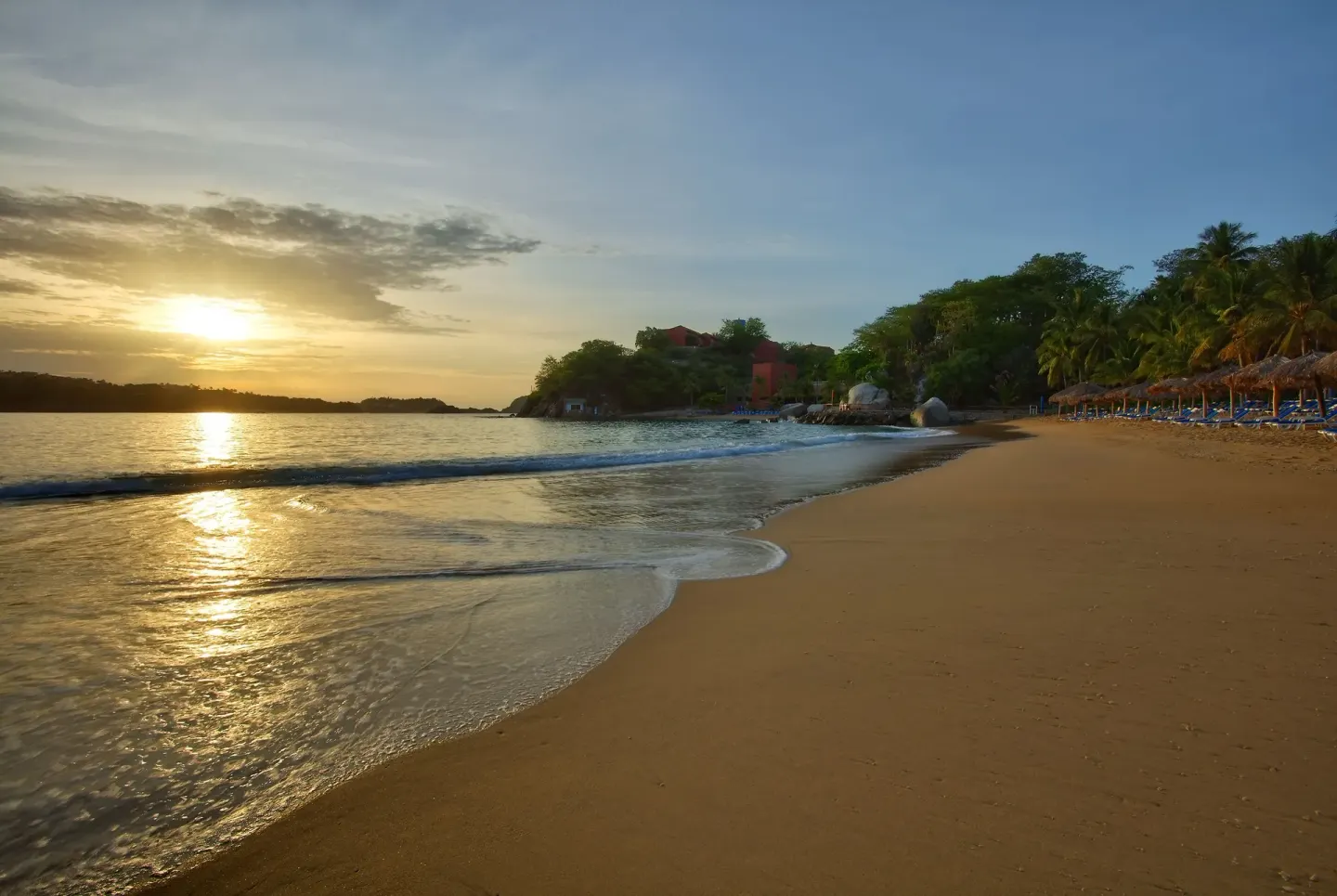 Sunset over the sandy beach and gentle surf at Las Brisas Huatulco.