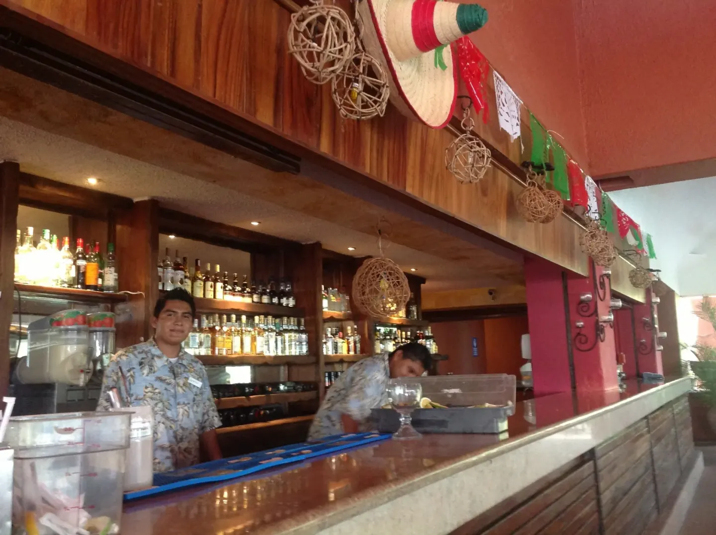 Bar counter with staff, bottles, and Mexican decorations at Las Brisas Huatulco.