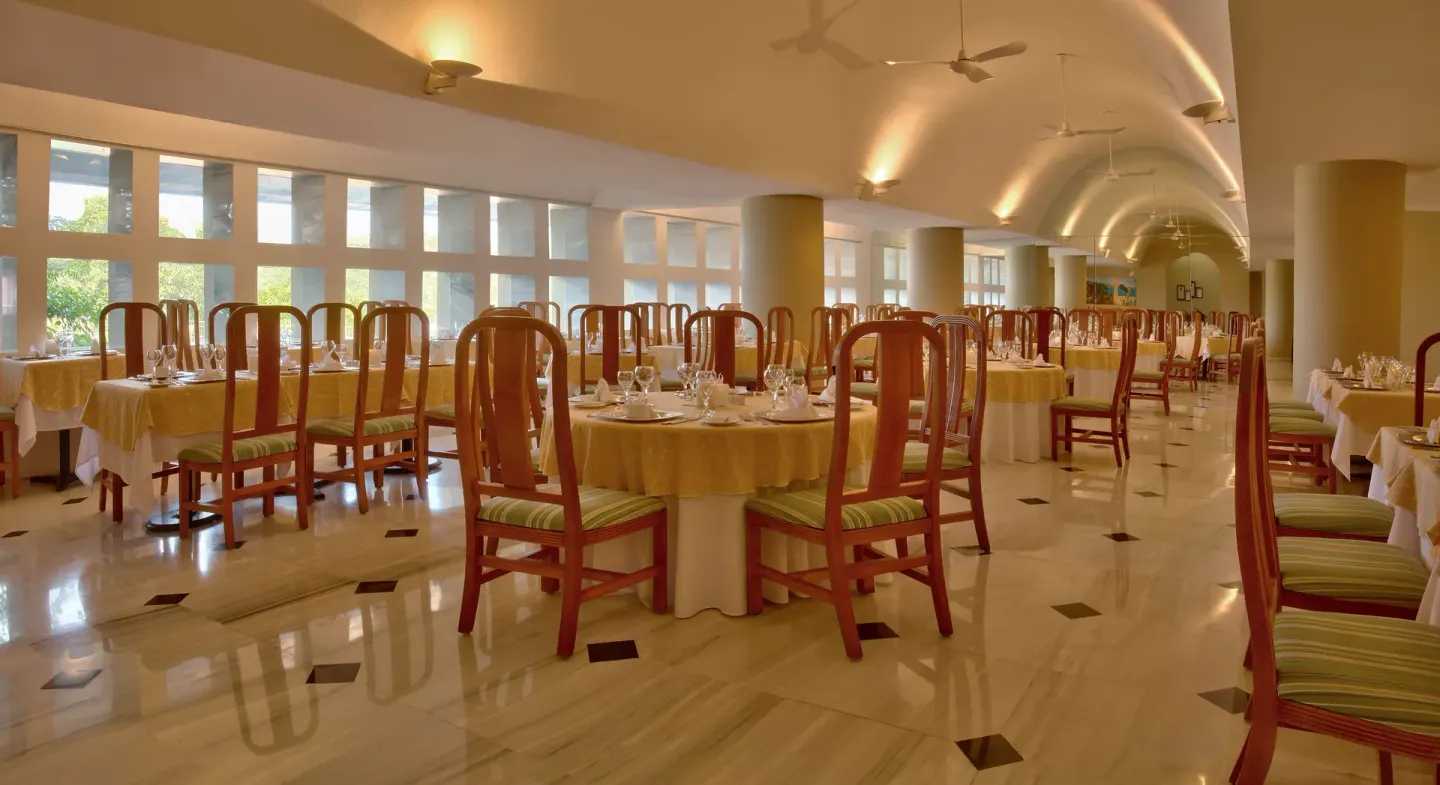 Bright indoor dining room with yellow tablecloths at Las Brisas Huatulco.