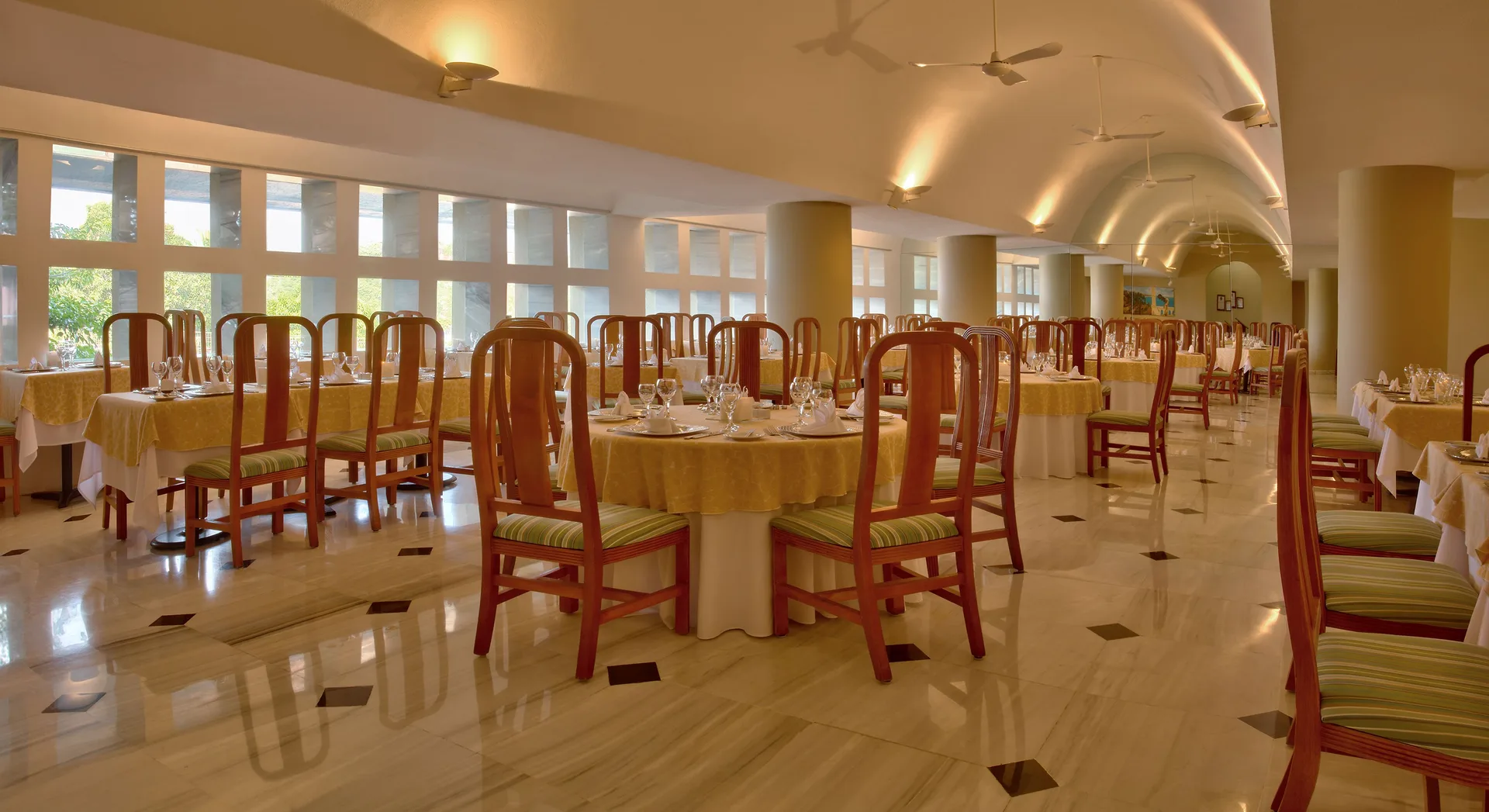 Bright indoor dining room with yellow tablecloths at Las Brisas Huatulco.