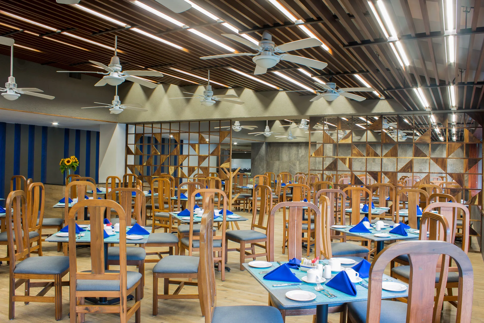 Dining room with blue napkins and wood chairs at Las Brisas Huatulco.