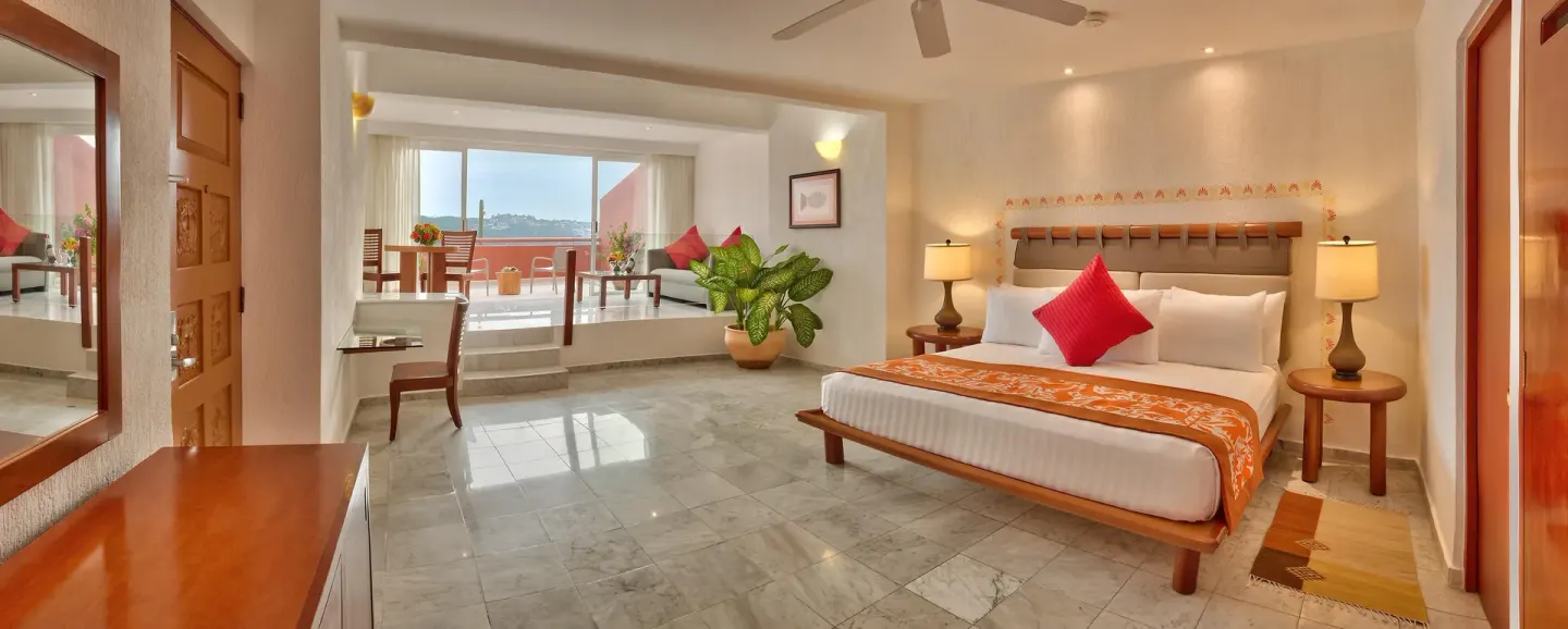 King-bed suite with sitting area and ocean-facing windows at Las Brisas Huatulco.