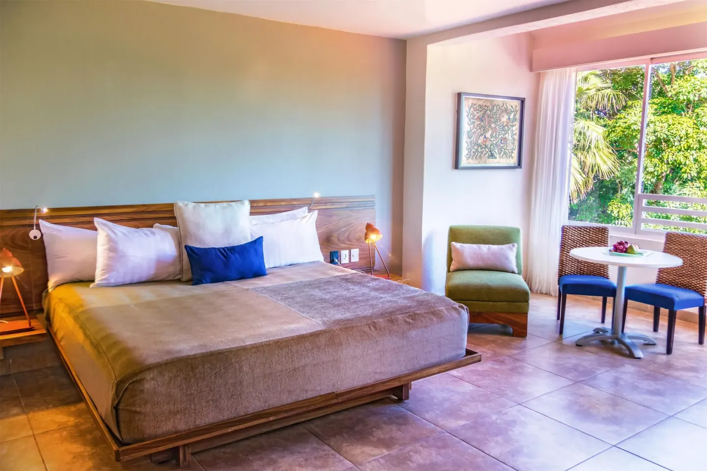 Deluxe Room king bed with seating area by the window at Las Brisas Huatulco.