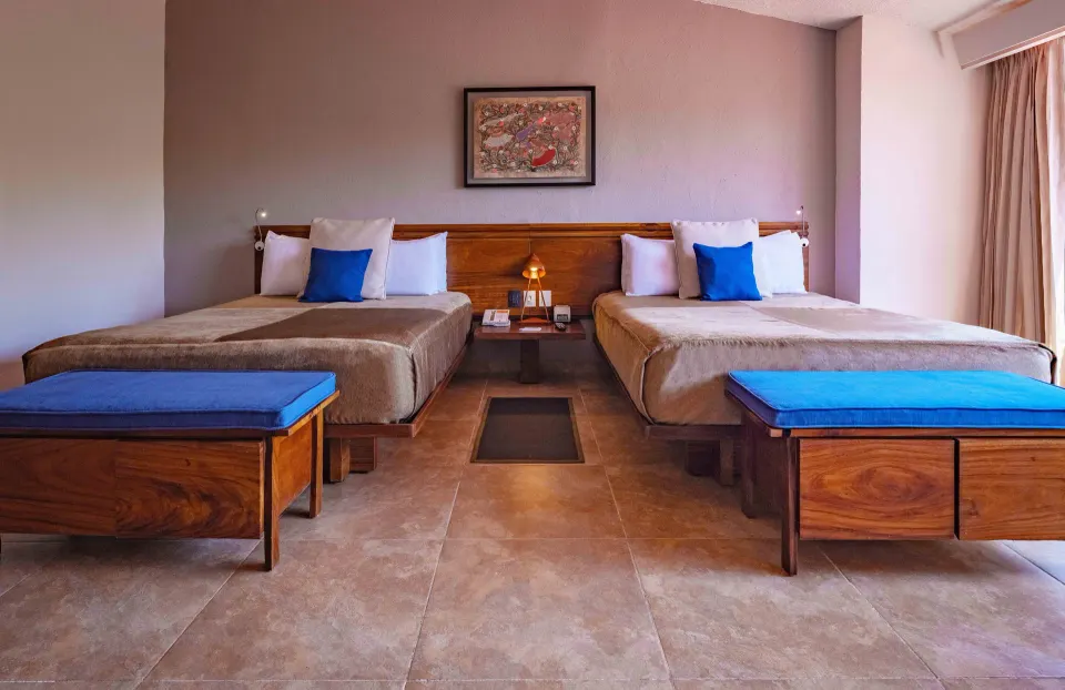 Deluxe Room with two beds and blue-cushioned benches at Las Brisas Huatulco.