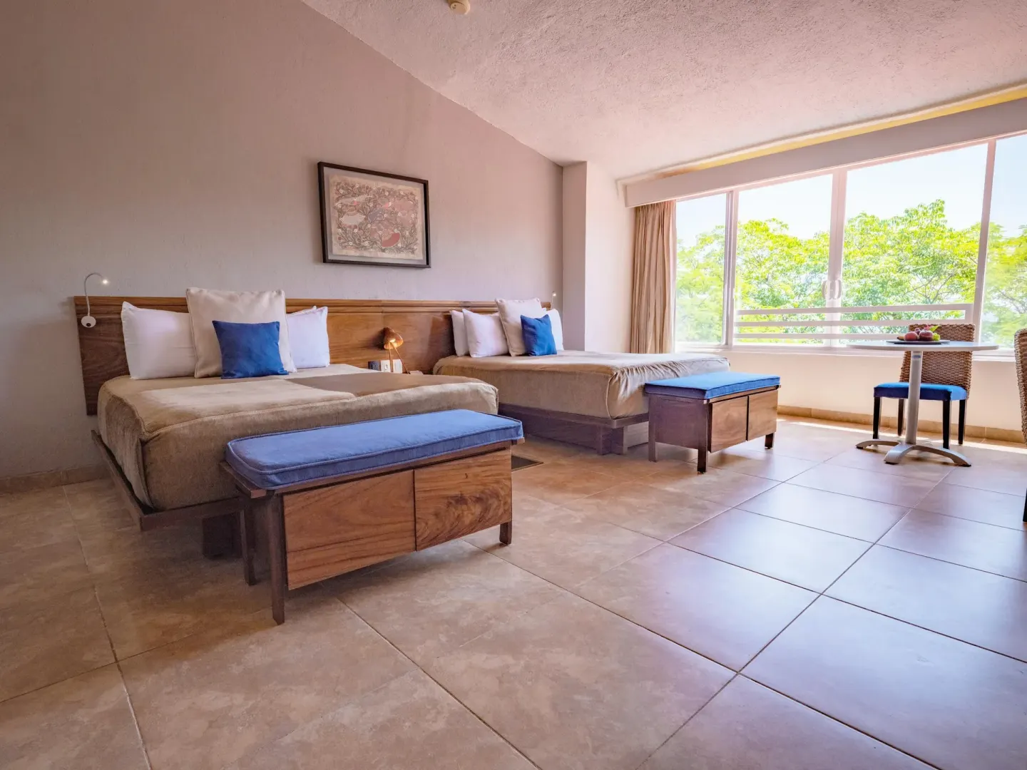 Deluxe Room with two beds, benches, and a window table at Las Brisas Huatulco.