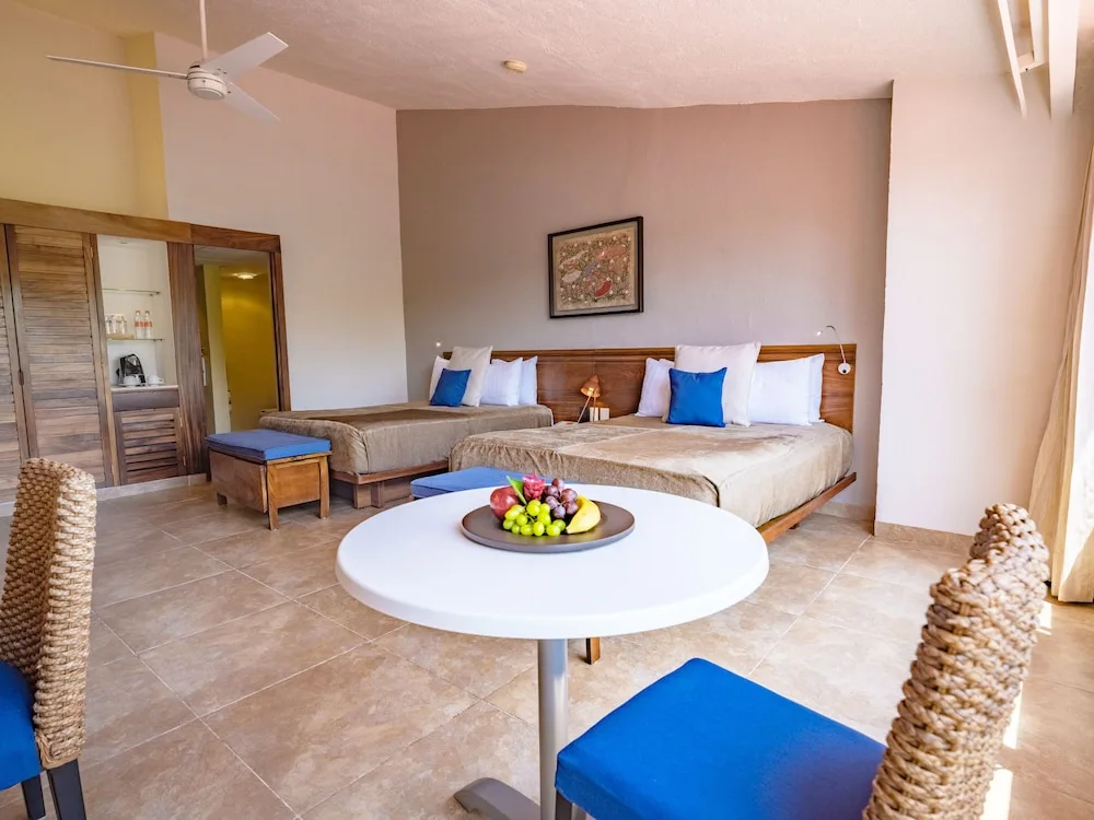 Deluxe room with two beds, fruit plate and seating area at Las Brisas Huatulco.