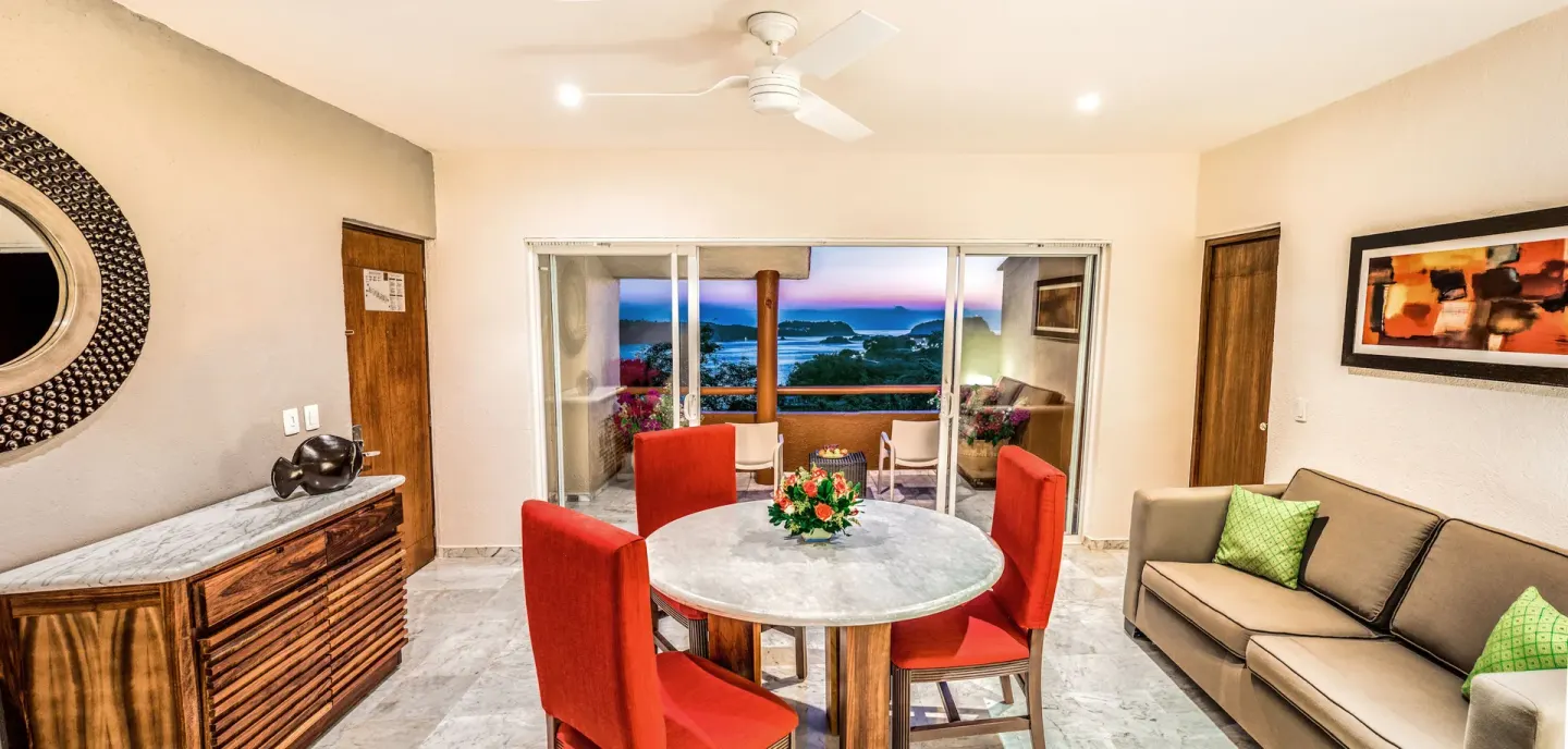 Junior Suite living and dining area with balcony view at Las Brisas Huatulco.