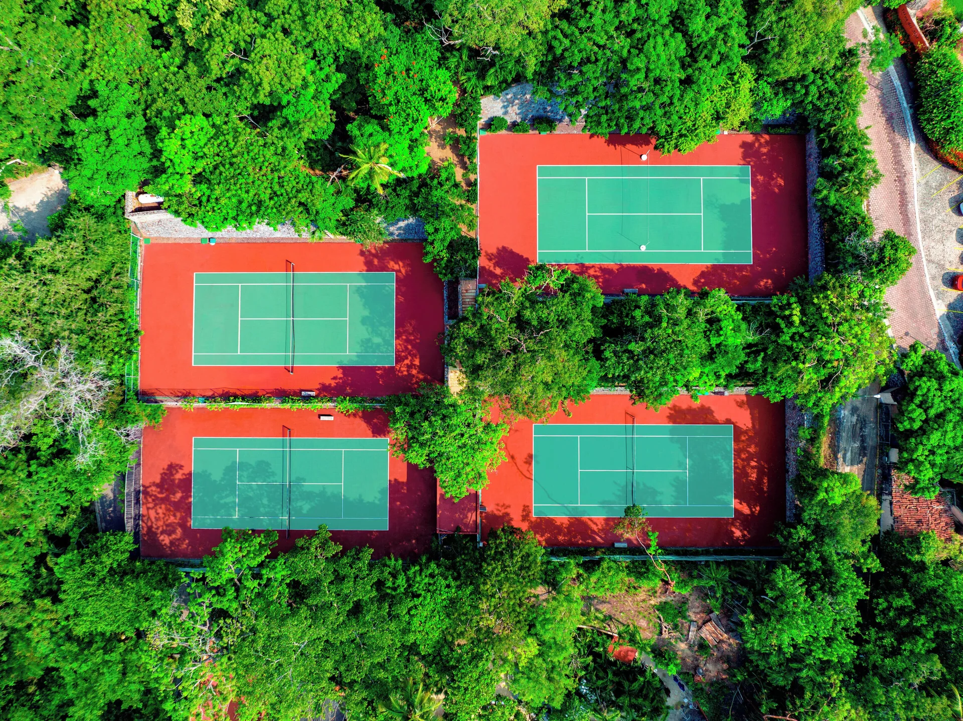 Aerial view of four tennis courts set among dense green trees at Las Brisas Ixtapa.