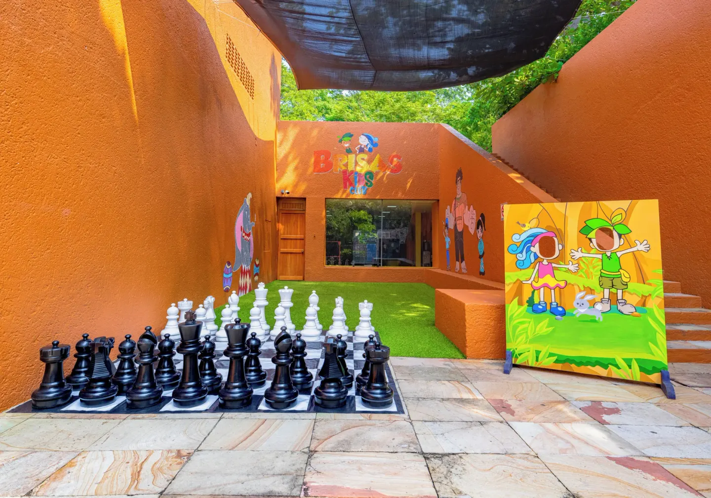 Outdoor kids club courtyard with giant chess pieces and orange walls at Las Brisas Ixtapa.