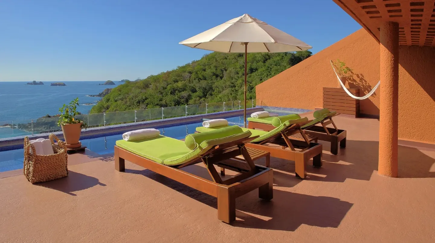 Pool terrace with green loungers, umbrella, hammock, and ocean view at Las Brisas Ixtapa.
