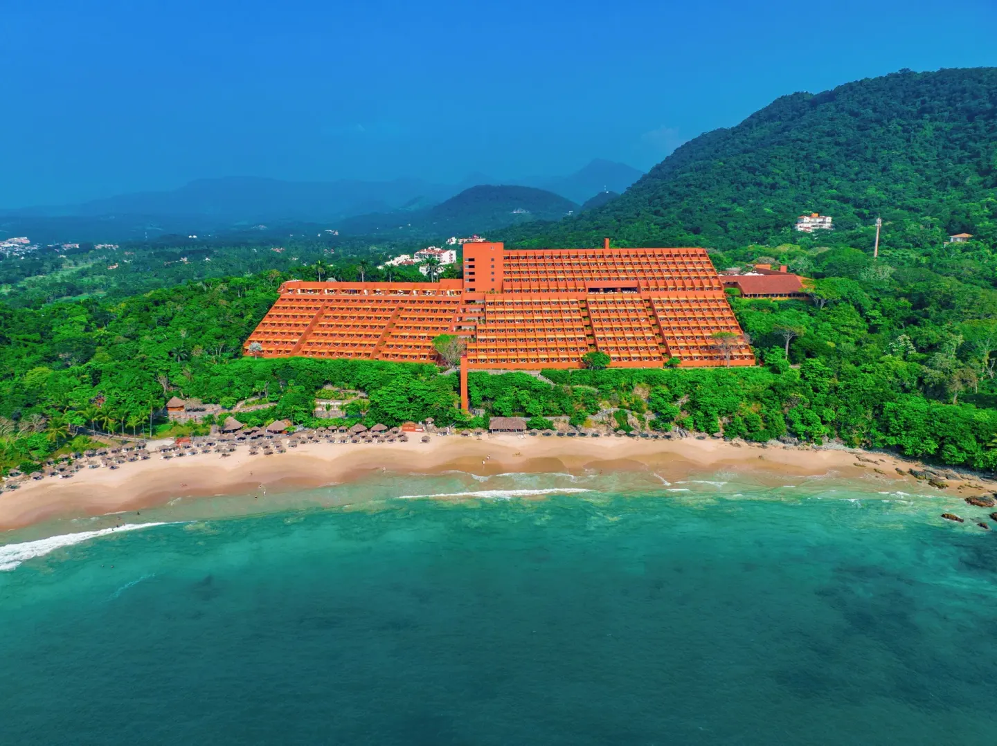 Front aerial view of Las Brisas Ixtapa above the beach and clear ocean.