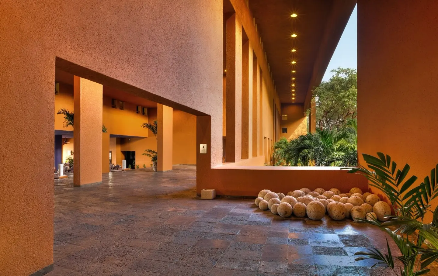 Open-air corridor with orange walls and stone floors at Las Brisas Ixtapa.