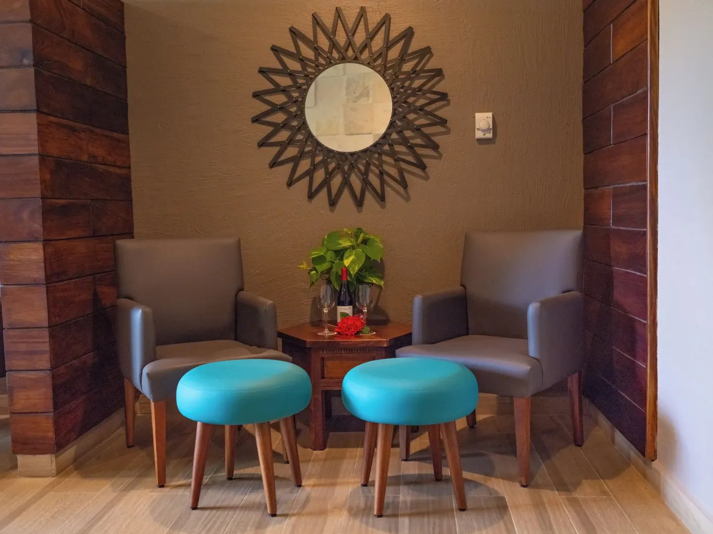 Small spa seating nook with two chairs, turquoise stools, and a decorative mirror at Las Brisas Ixtapa.