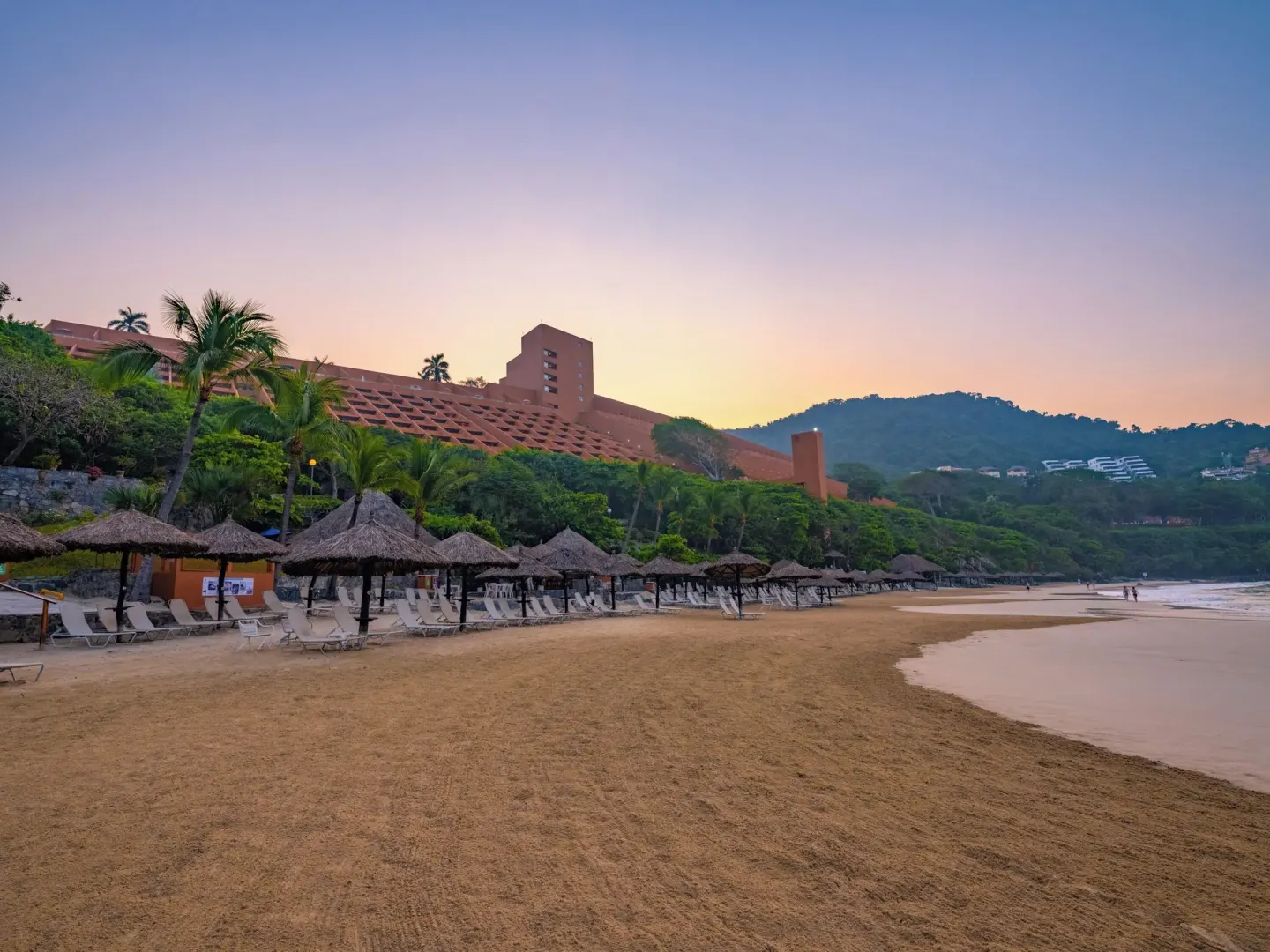 Beach loungers, palapas, and the hillside resort building at Las Brisas Ixtapa.