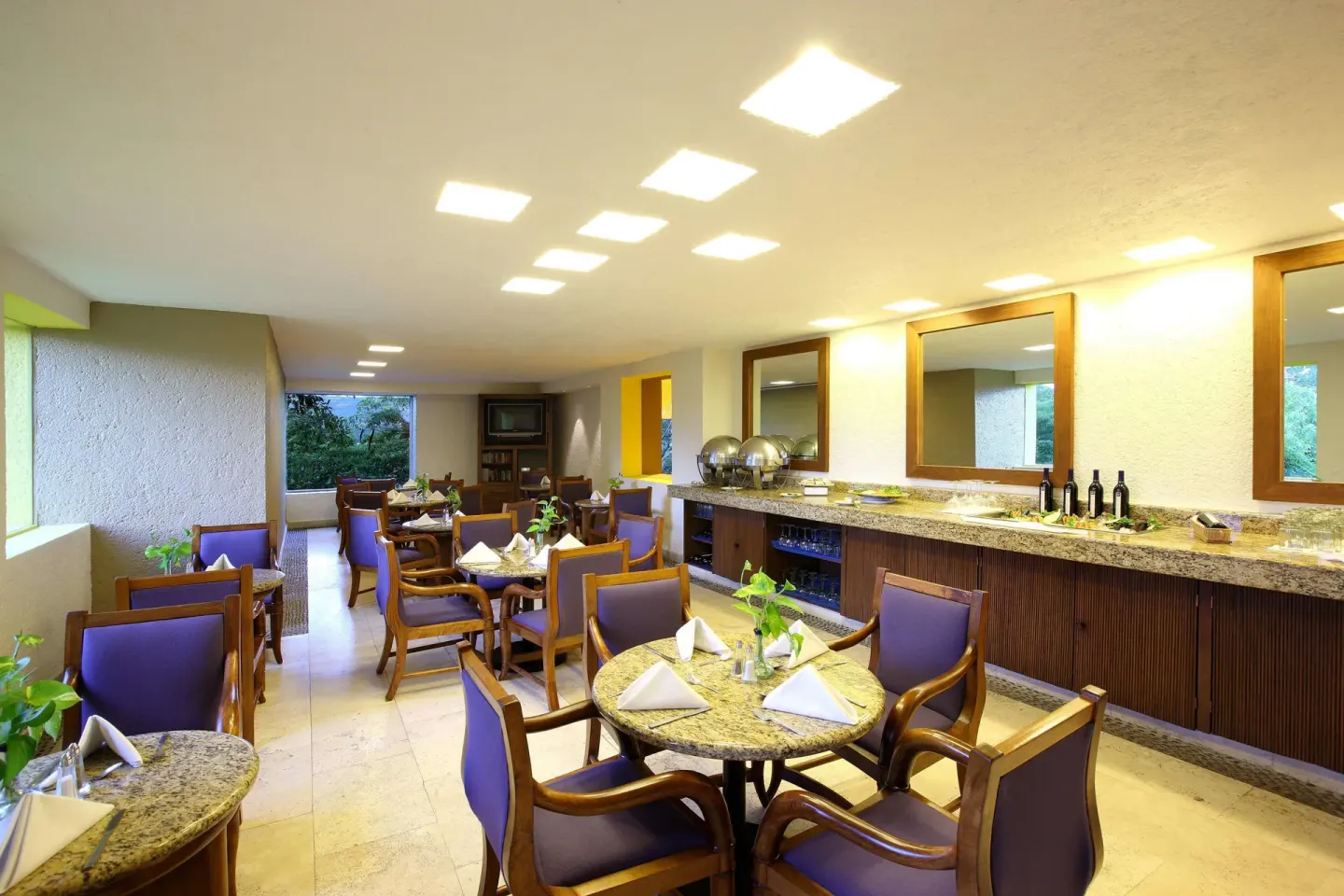 Buffet dining room with round tables and counter service at Las Brisas Ixtapa.