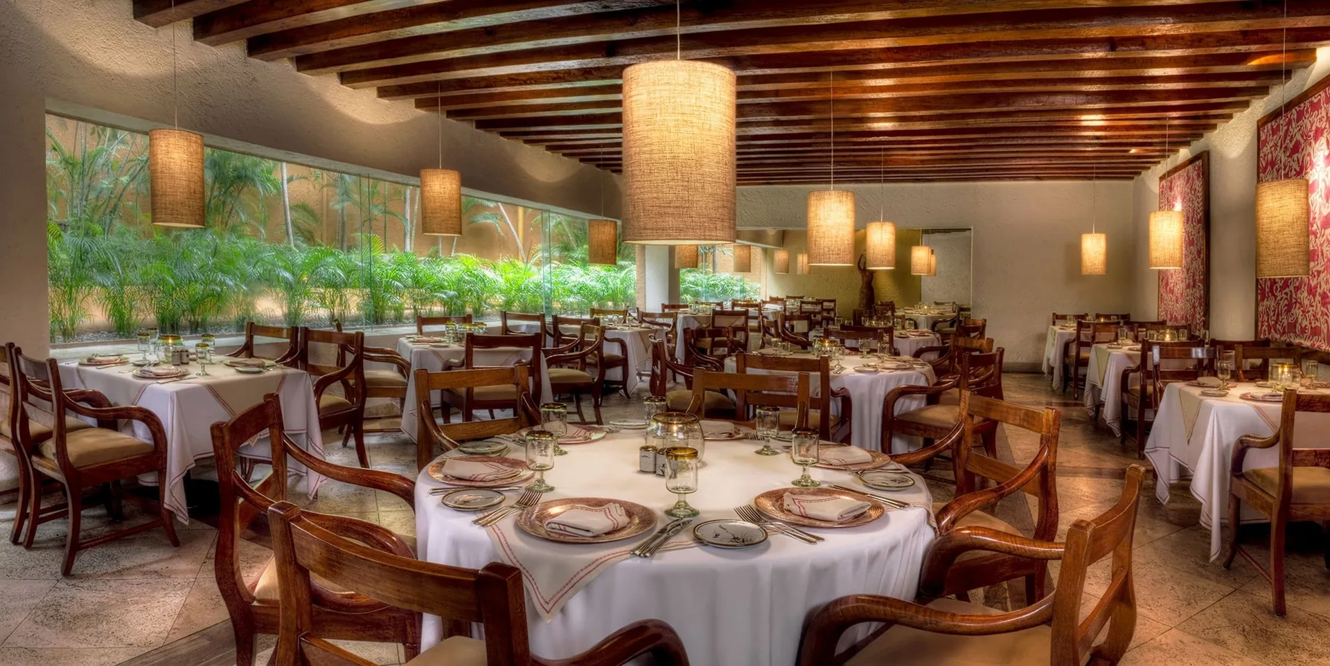 Restaurant dining room with garden windows and pendant lamps at Las Brisas Ixtapa.