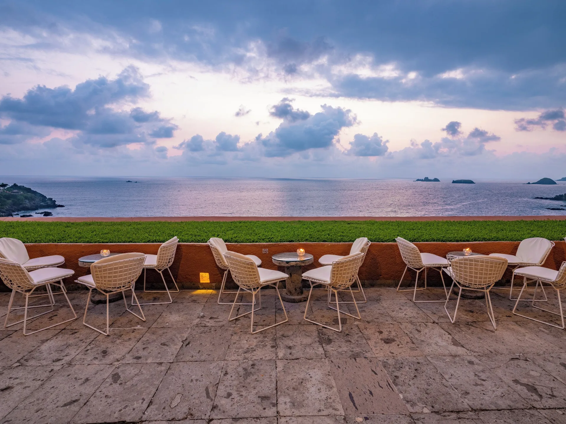 Terrace lounge seating faces the ocean beneath a cloudy evening sky at Las Brisas Ixtapa.