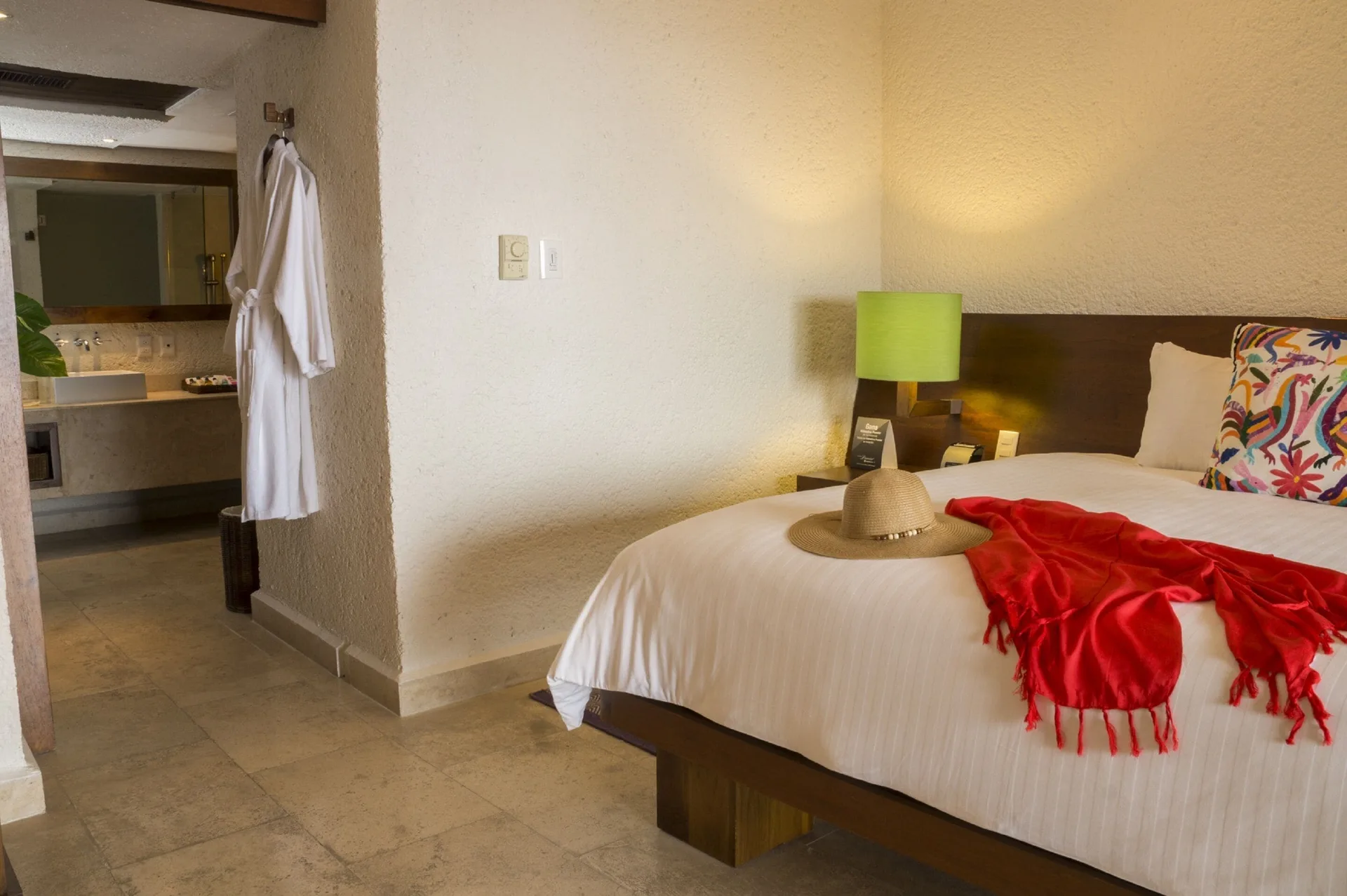Deluxe Grand Bed guest room at Las Brisas Ixtapa with bed, robe, and open bathroom area.
