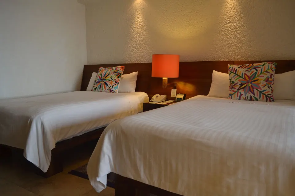 Deluxe Grand room with two beds and orange bedside lamp at Las Brisas Ixtapa.