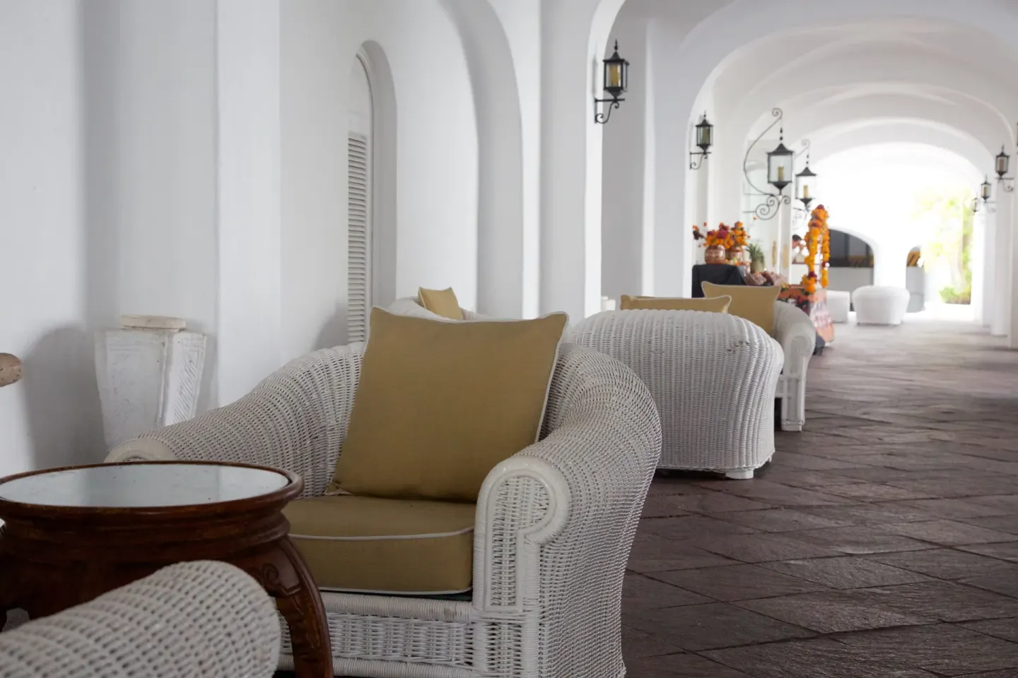 Arched corridor lounge at Las Hadas with white wicker chairs and wall lanterns.
