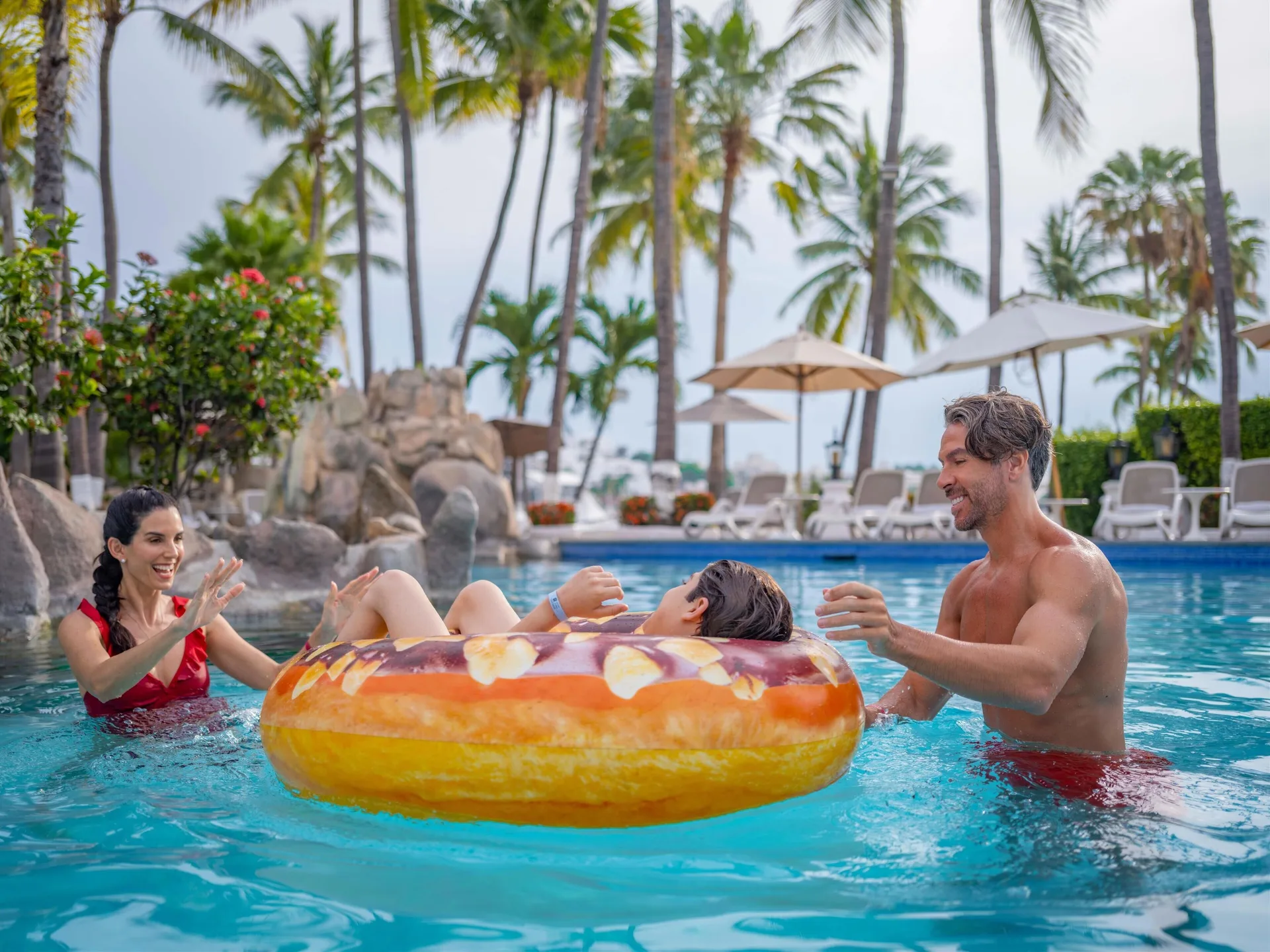 Family playing with an inflatable ring in the pool at Las Hadas.