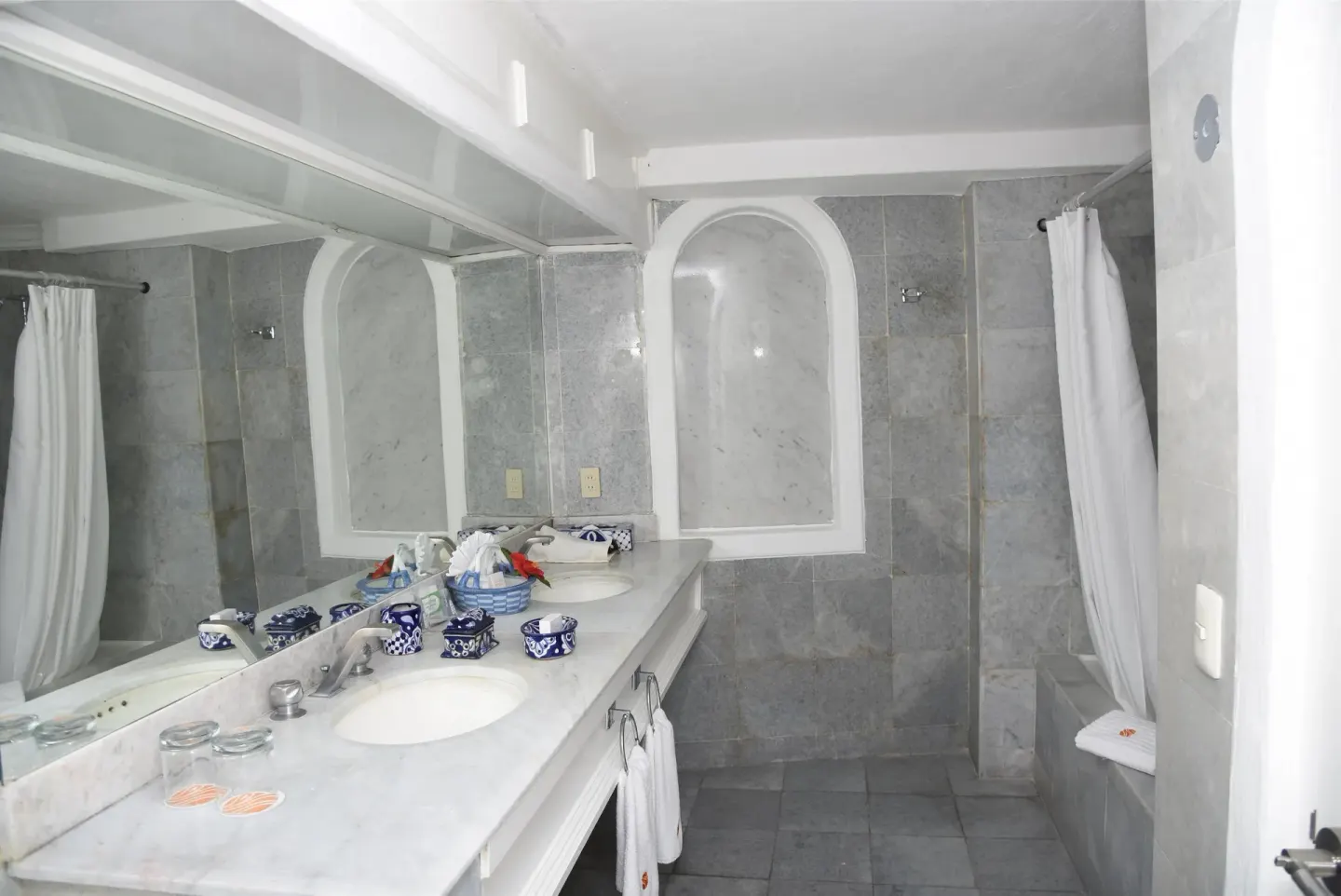 Gray-tiled bathroom with long vanity, shower curtain, and tub at Las Hadas.