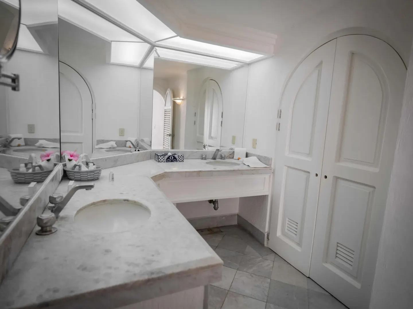 Guest bathroom with two marble vanities and arched closet doors at Las Hadas.